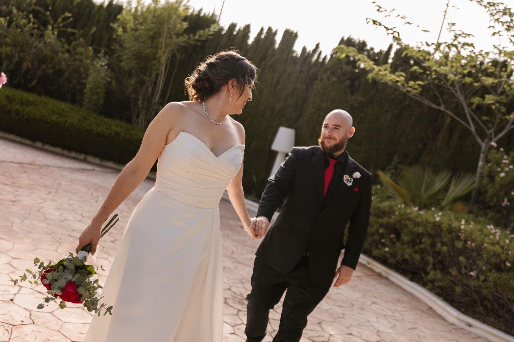 Una pareja recién casada camina de la mano y se sonríe